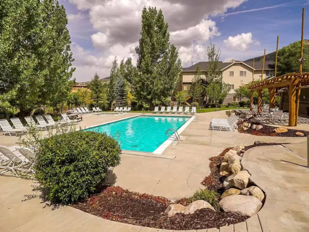 Resort-style seasonal pool with plenty of lounge chairs for sunbathing, plus a shaded pergola for relaxing in comfort between dips.