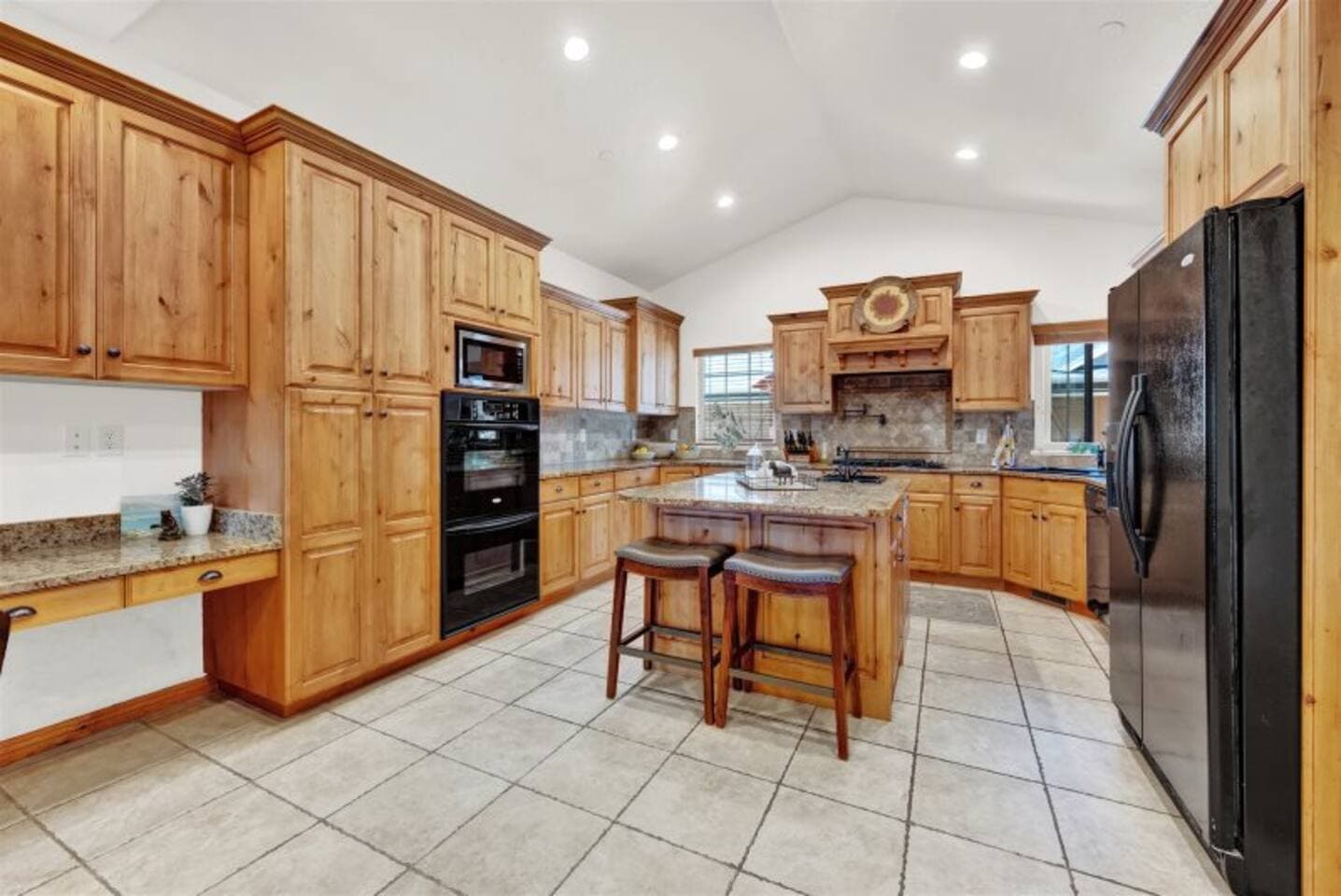 Chef’s kitchen fully stocked with cookware, dishes, and utensils—featuring granite countertops, double ovens, a gas stove top, and everything you need to whip up meals for a crowd.