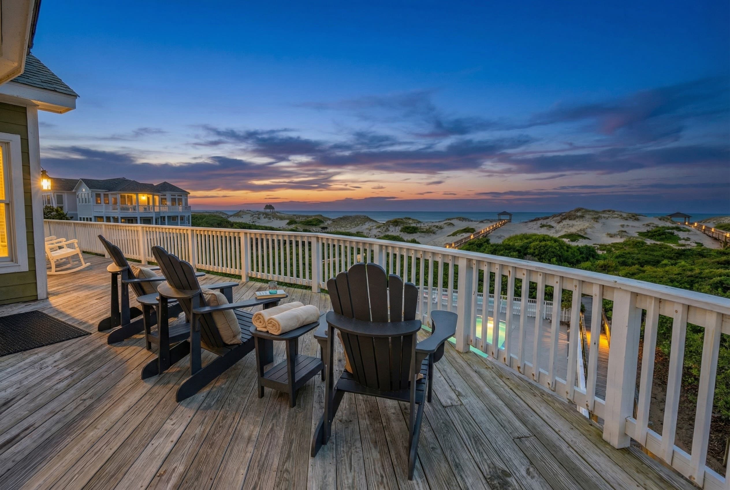 Golden sunset from the upper deck — Adirondack chairs positioned for uninterrupted Atlantic views as day turns to a magnificent Outer Banks evening