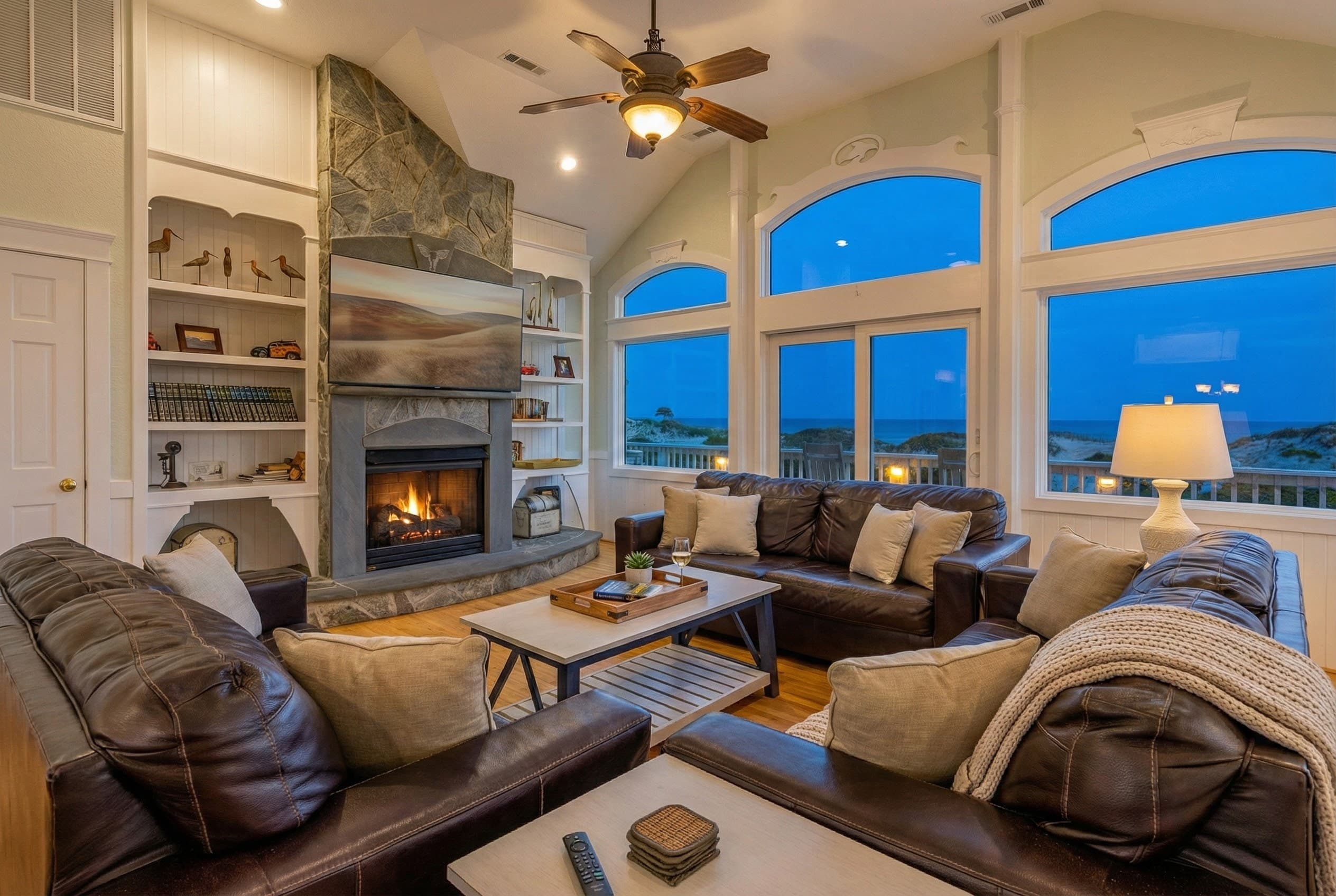 Elegant living space bathed in twilight — floor-to-ceiling windows frame the Atlantic while sophisticated interiors invite evening relaxation