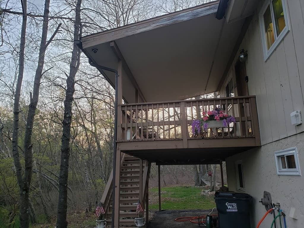 Grand entryway to the house is up the stairs to a covered deck overlooking the driveway. Straight back and to the right is the Den door. 
