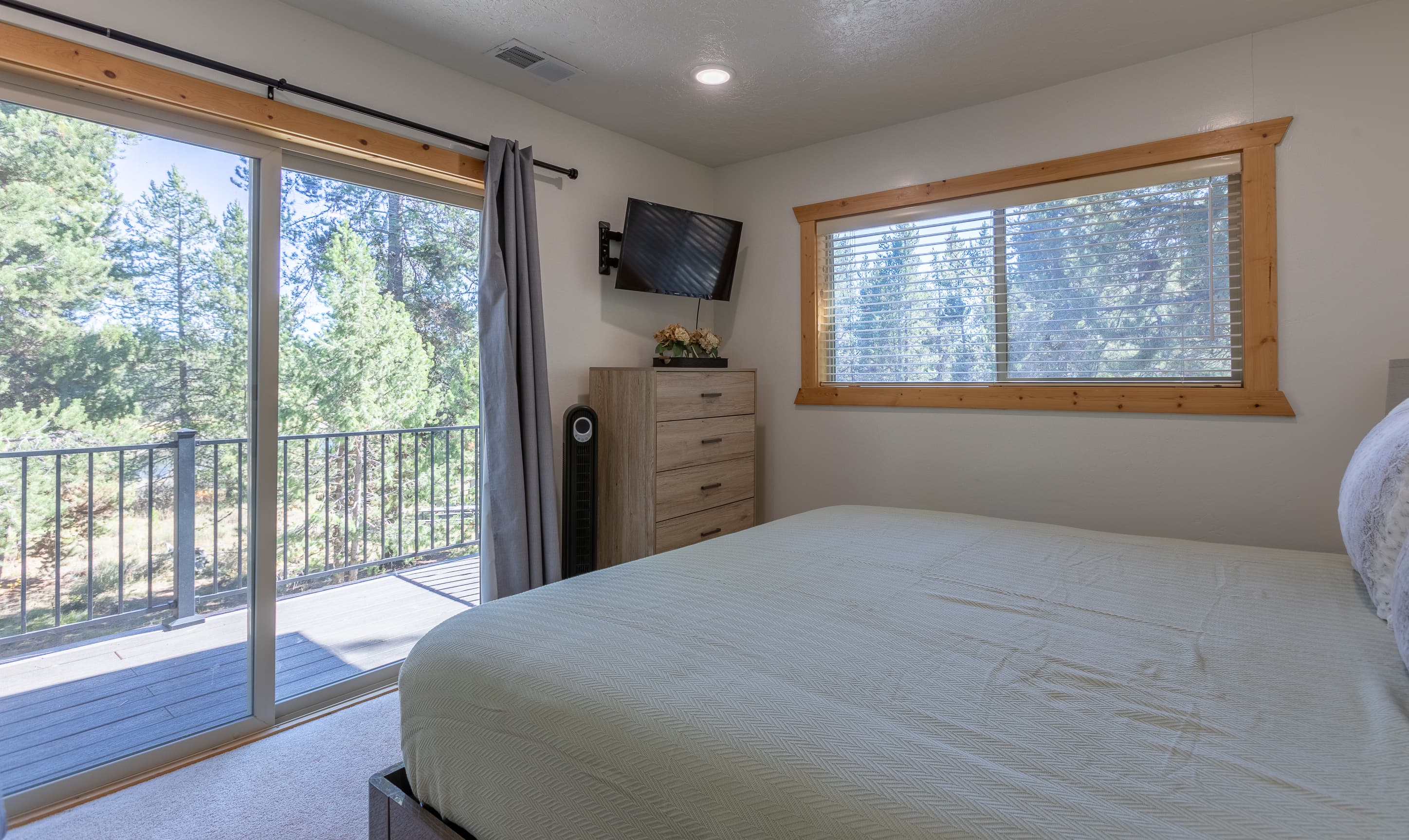 Third bedroom with TV, dresser & balcony access.