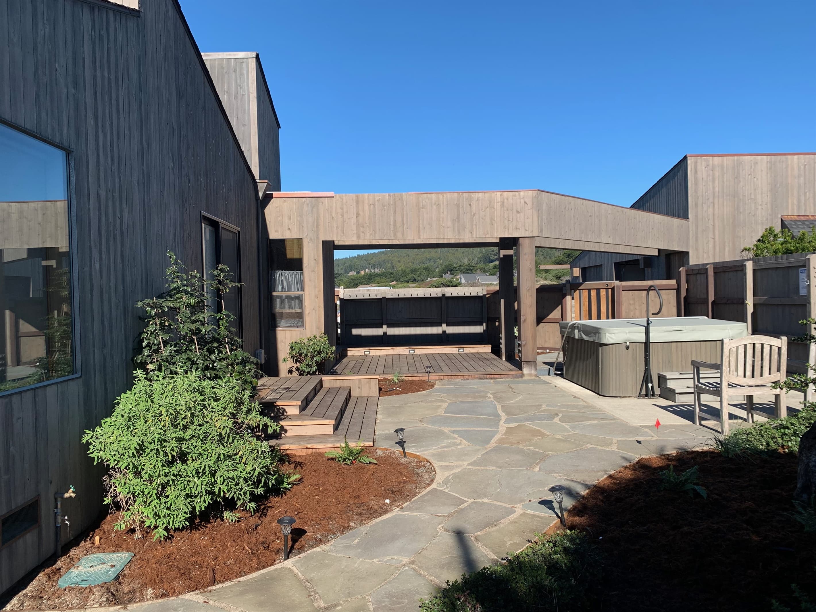 Courtyard charm: soak in the hot tub, lounge in the chairs, or practice yoga under the breezeway. Stroll along the stone paths framed by native flowers. Private deck access from the principal bedroom.
