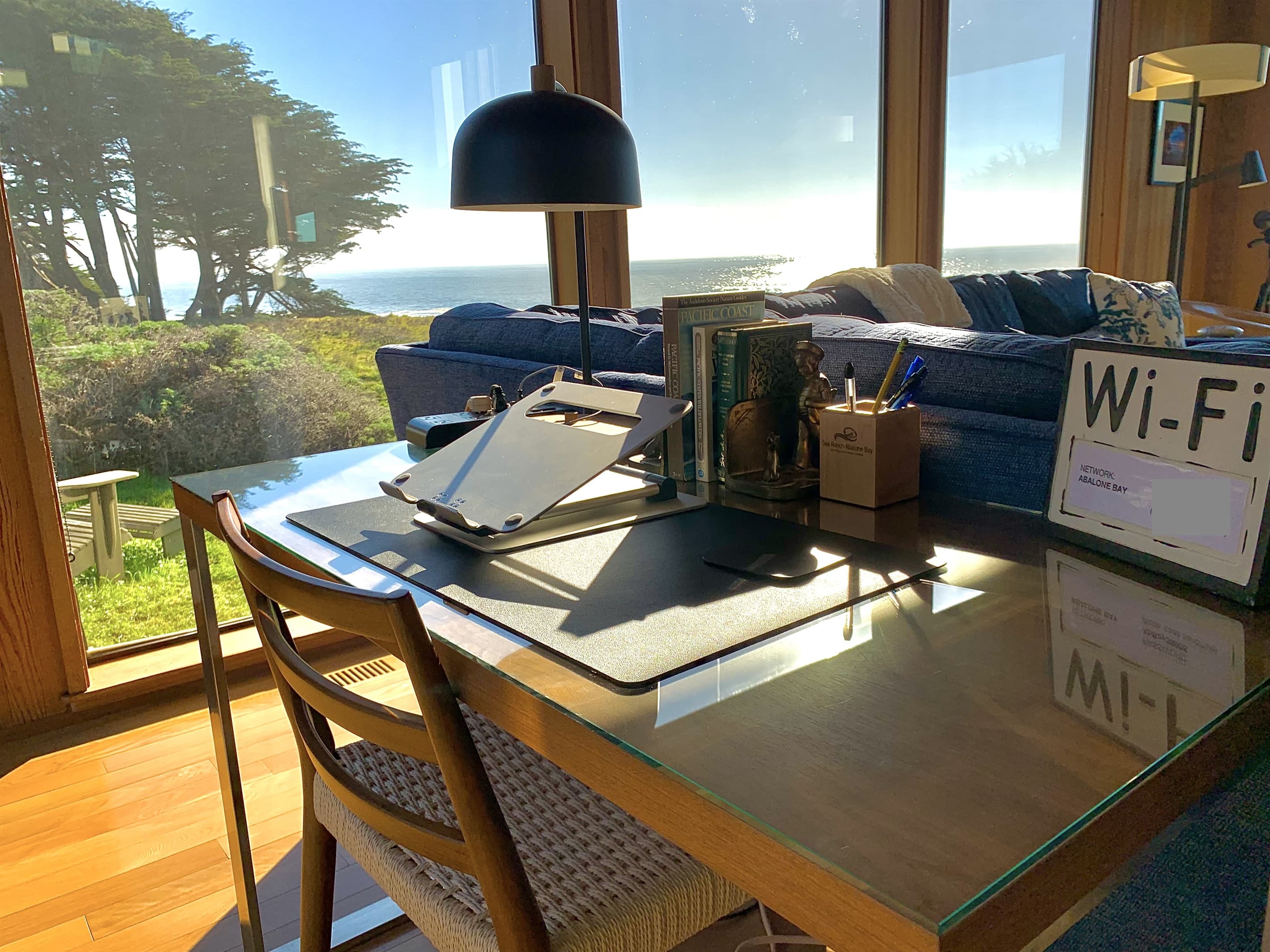 Elegant glass-topped writing desk with panoramic ocean views, ergonomic setup, and curated decor—ideal for focused productivity or creative flow, all supported by high-speed Wi-Fi.