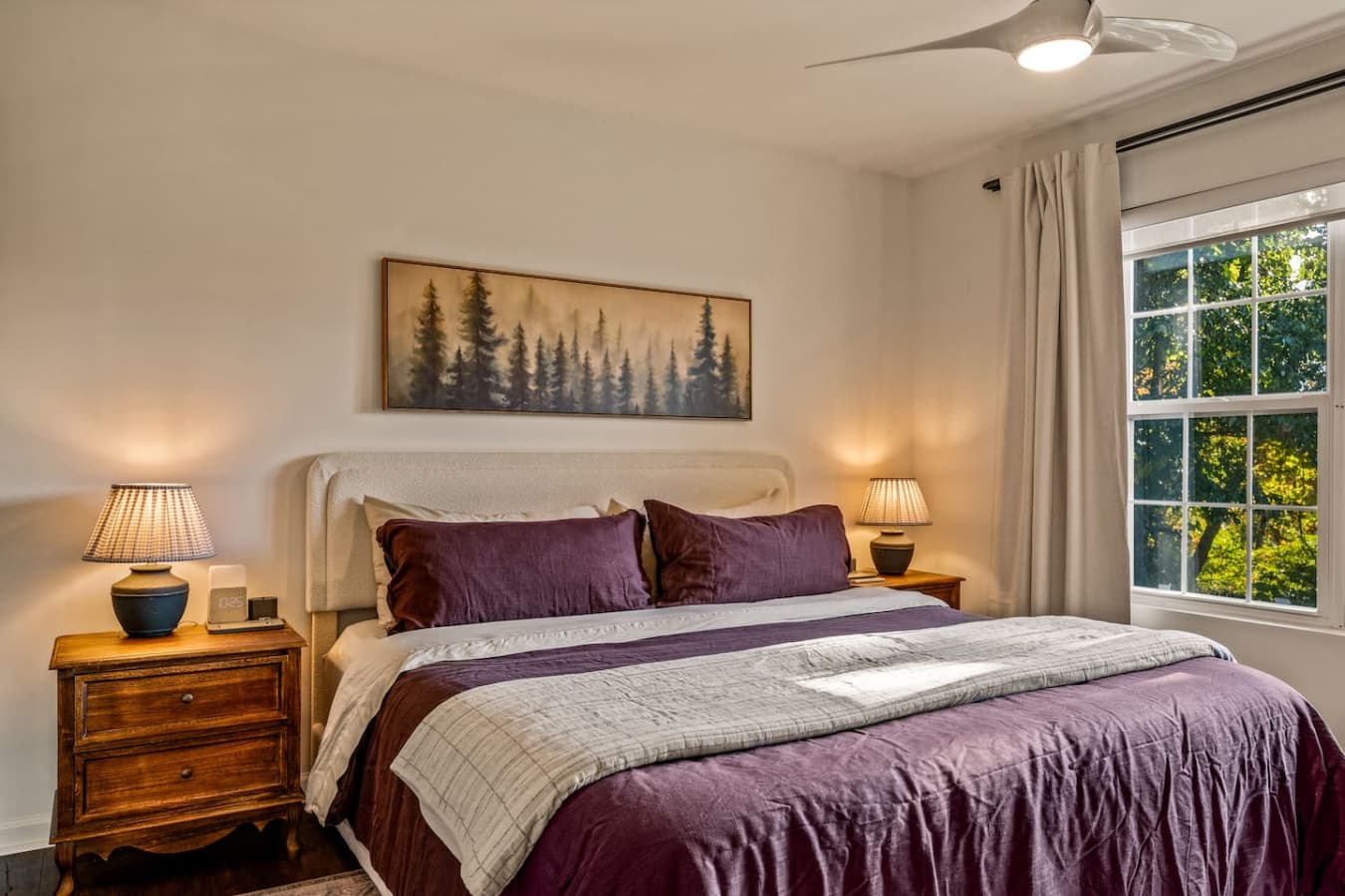 A plush, inviting bed sits at the center, offering the perfect spot to unwind while gazing at the rolling hills outside.