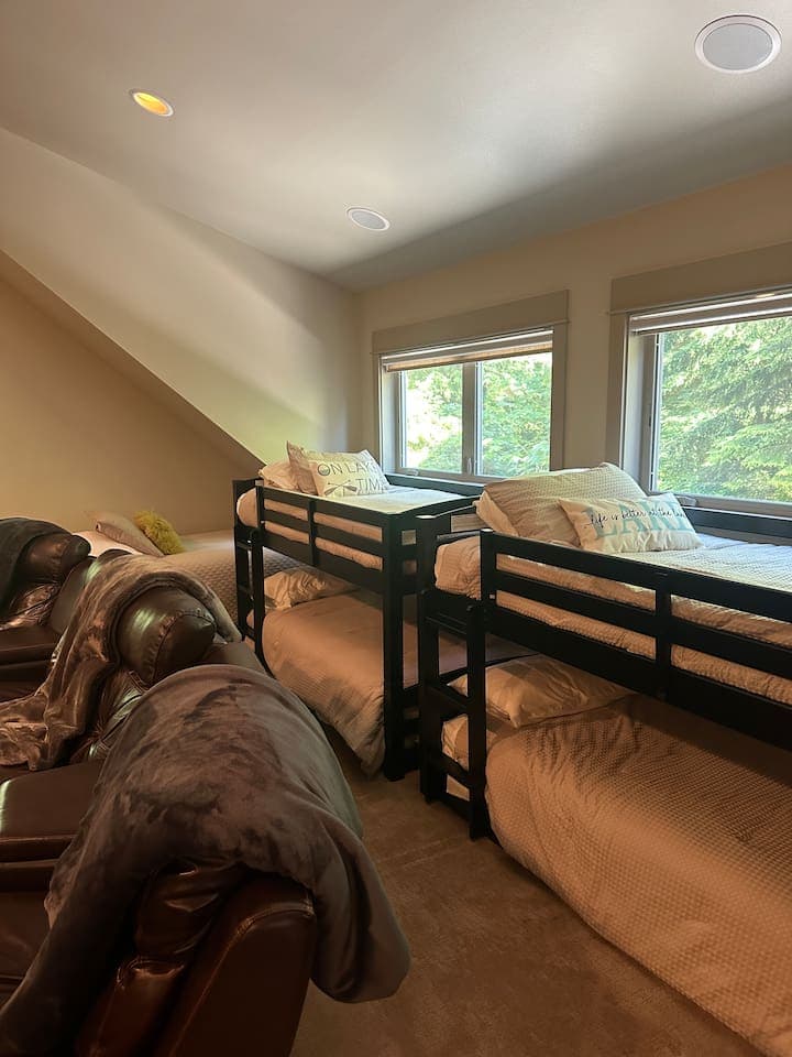 The bunk room sleeps five, featuring two low-profile bunk beds and an additional twin bed, creating a cozy retreat-like space. The twin bed can comfortably accommodate an adult, while the bunks are only suited for children.
