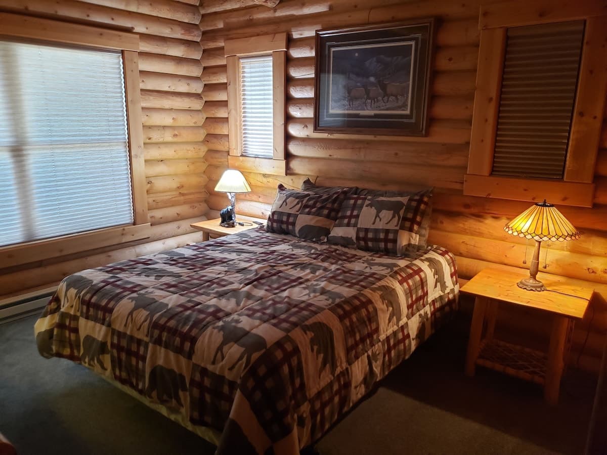 Bedroom 1: queen bed, enjoy tasteful cabin decor, warm lighting, and a large window.