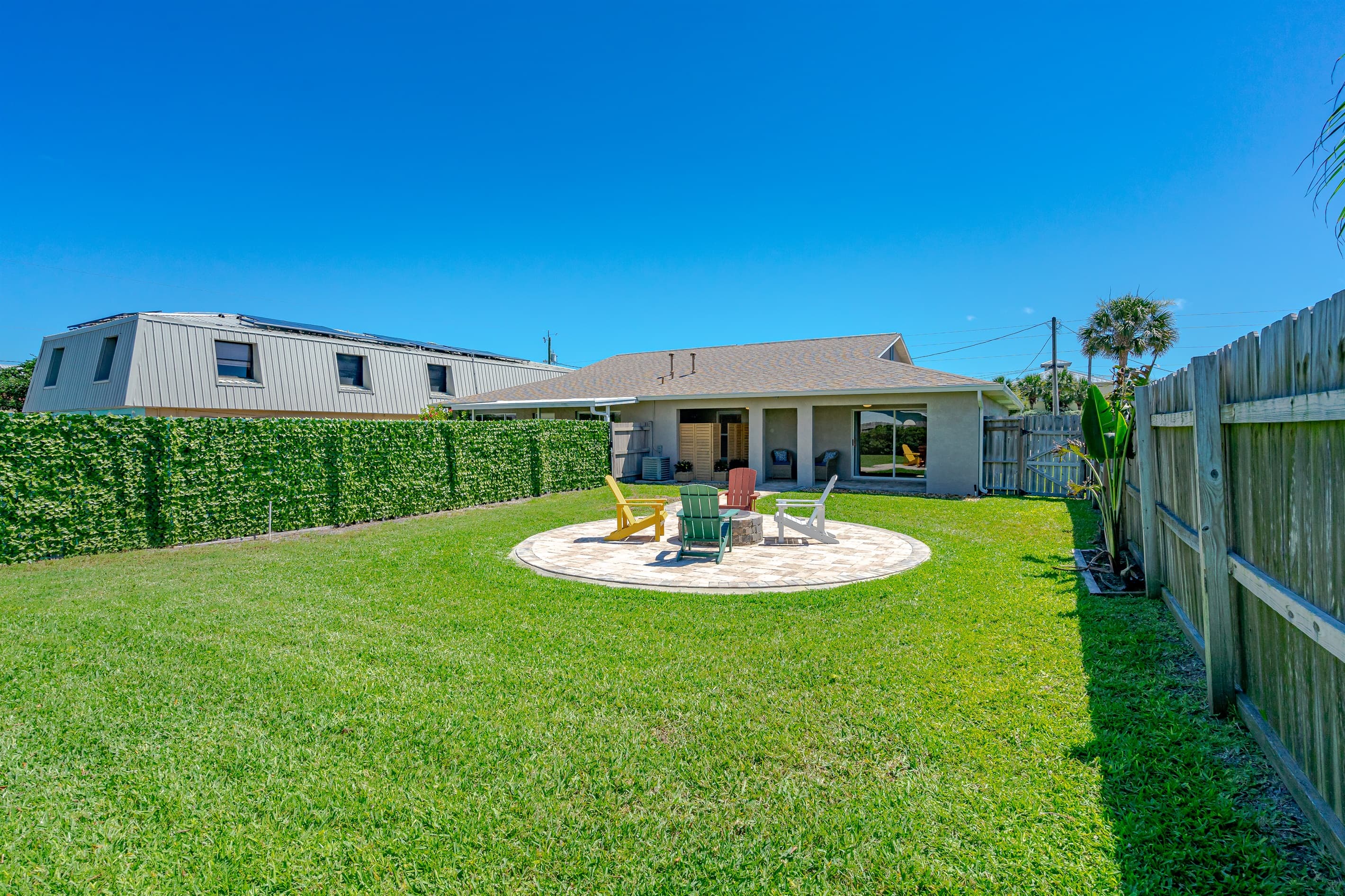 Island Time Fenced Backyard w/ Couches and Adirondack Chairs