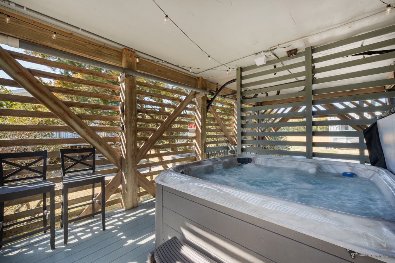 Covered deck w/ hot tub & bar seating, a relaxing spot to unwind outdoors