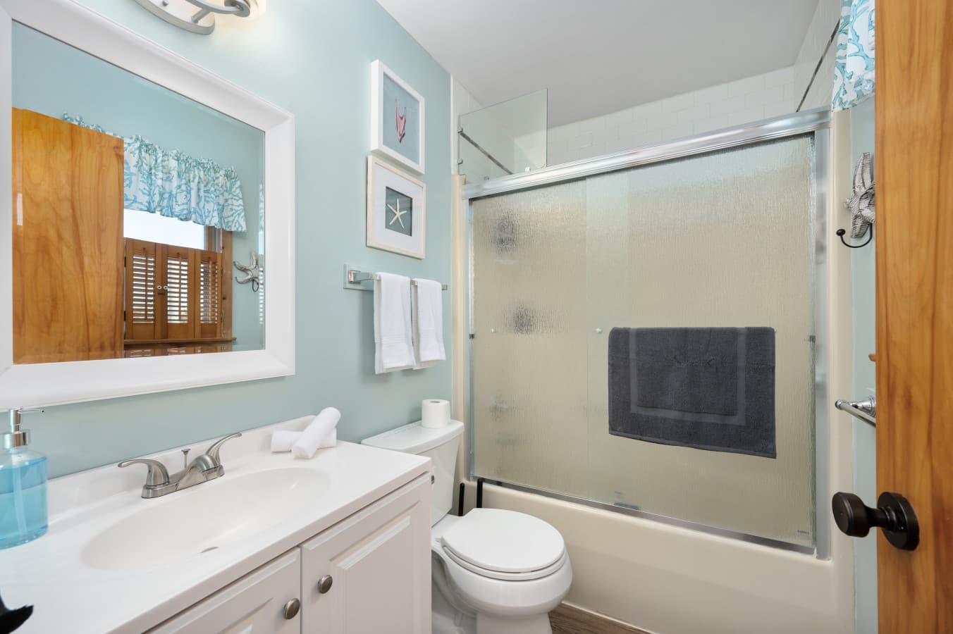 Bright bathroom w/ glass-enclosed shower, sink vanity & fresh, clean finishes