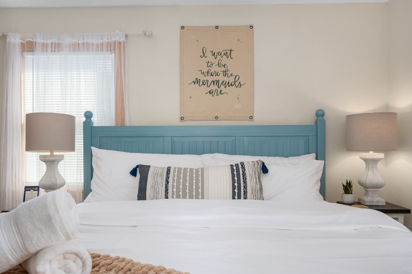 Serene bedroom w/ blue headboard, soft linens & bedside lighting for a restful stay