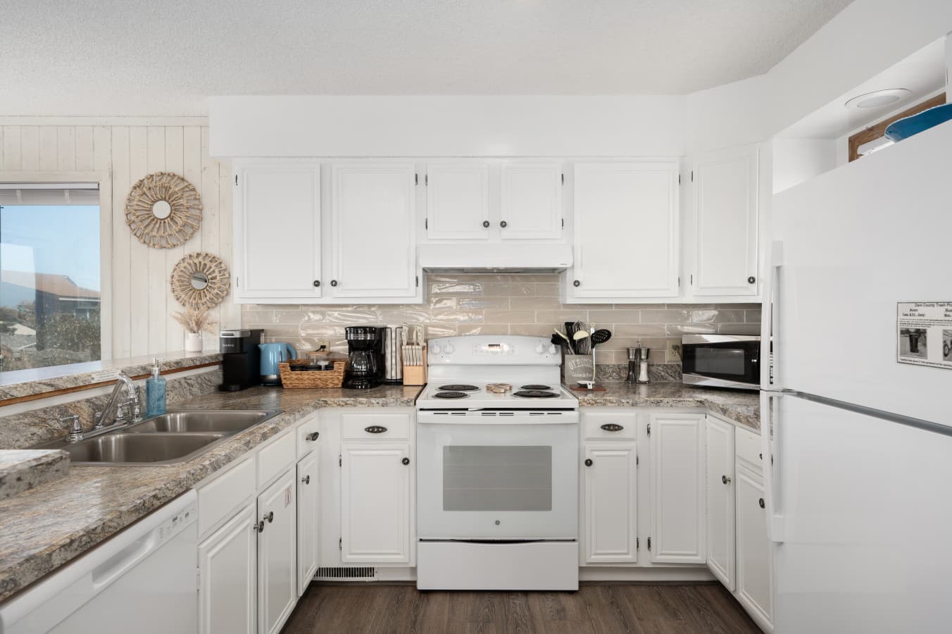 Bright kitchen w/ white cabinetry, modern appliances & plenty of counter space