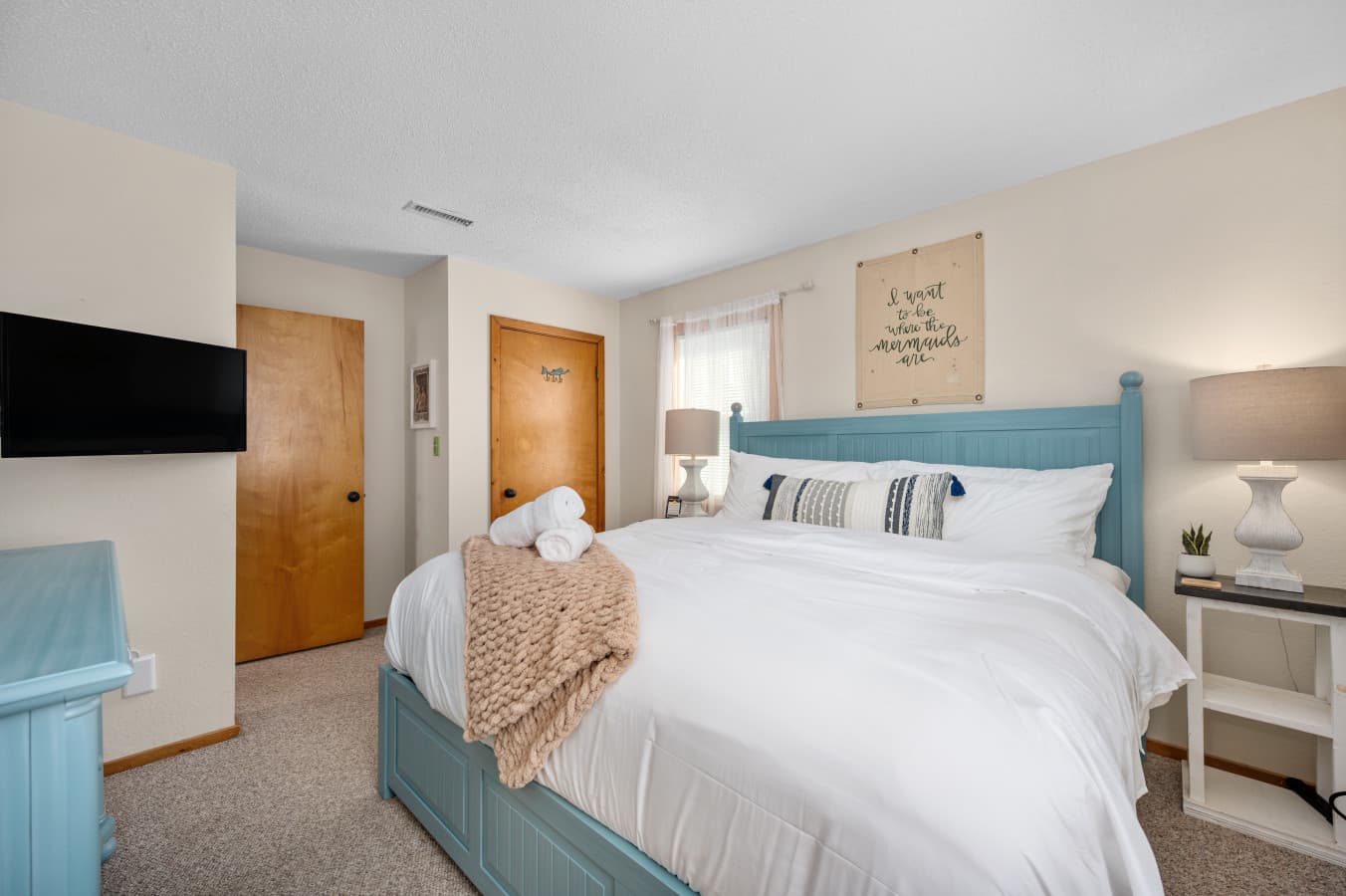 Bright bedroom w/ plush bedding, bedside lighting & soft neutral tones