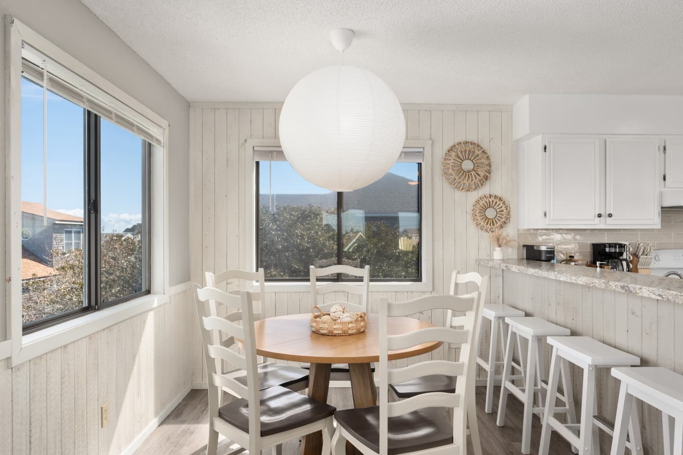 Sunlit dining area w/ large windows & table set for shared meals