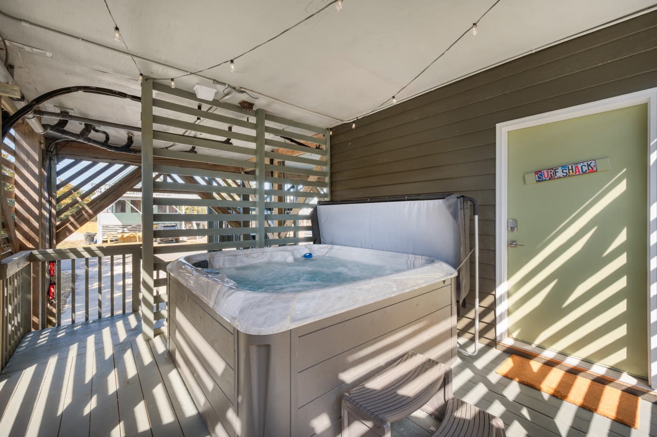 Covered deck w/ hot tub surrounded by privacy slats for a relaxing soak