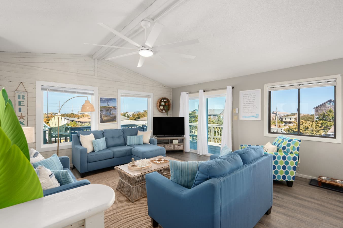 Bright living room w/ blue sofas, large windows & coastal decor throughout