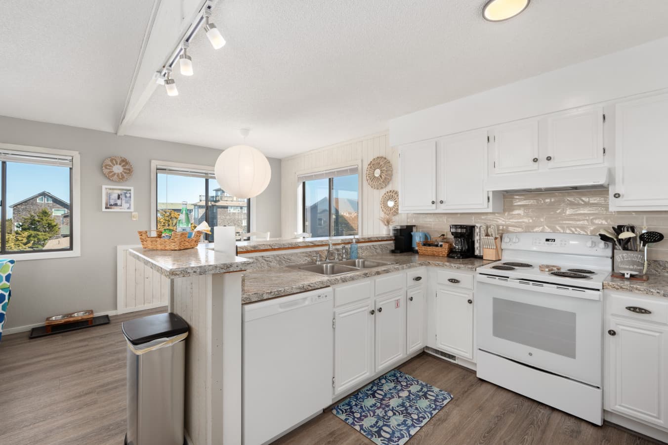Open kitchen w/ white cabinetry, ample counters & track lighting above