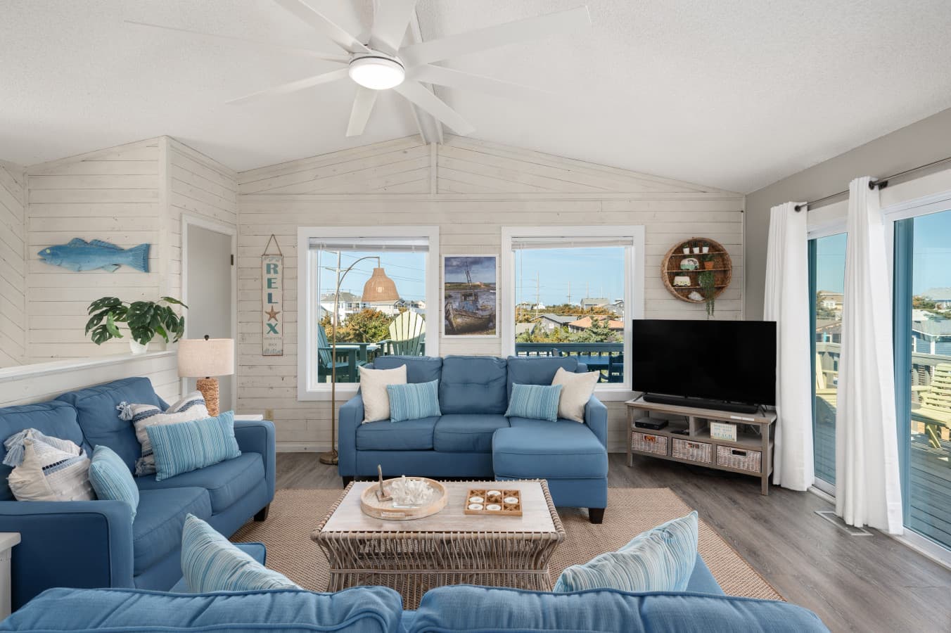 Bright living room w/ comfy seating, TV & large windows letting in plenty of natural light