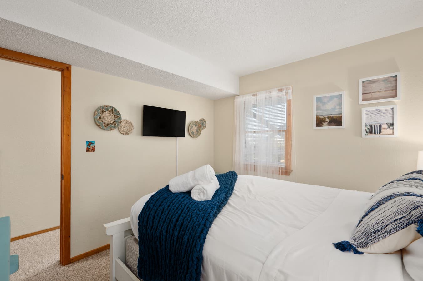 Comfortable bedroom w/ soft bedding, TV & warm natural light