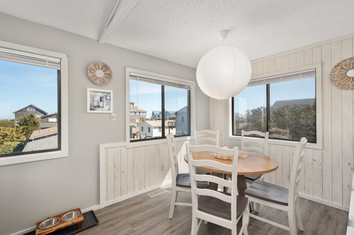 Dining nook w/ round table, large windows & bright coastal ambiance