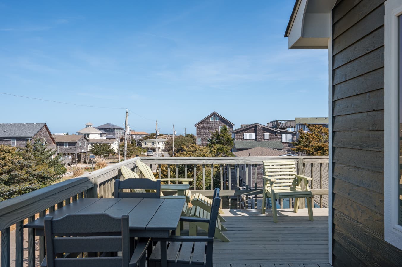 Sunny deck w/ dining table, bench seating & wide views over the surrounding cottages.
