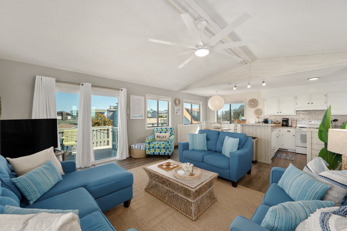 Spacious living room w/ blue sofas, large windows & easy access to the deck