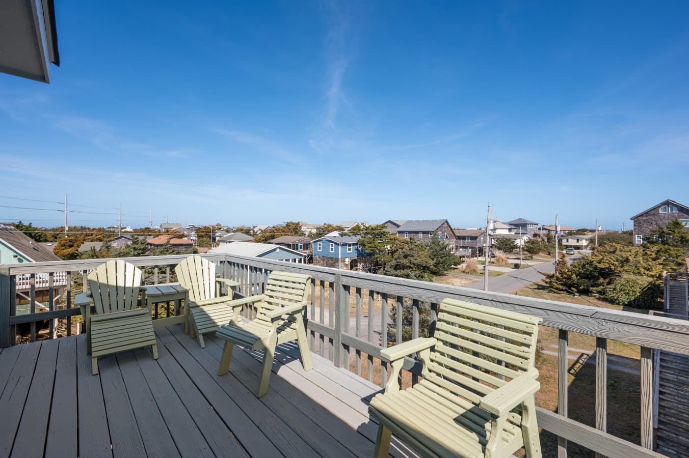 Deck seating w/ painted wood benches & Adirondack chairs lined along the rail for slow afternoons.
