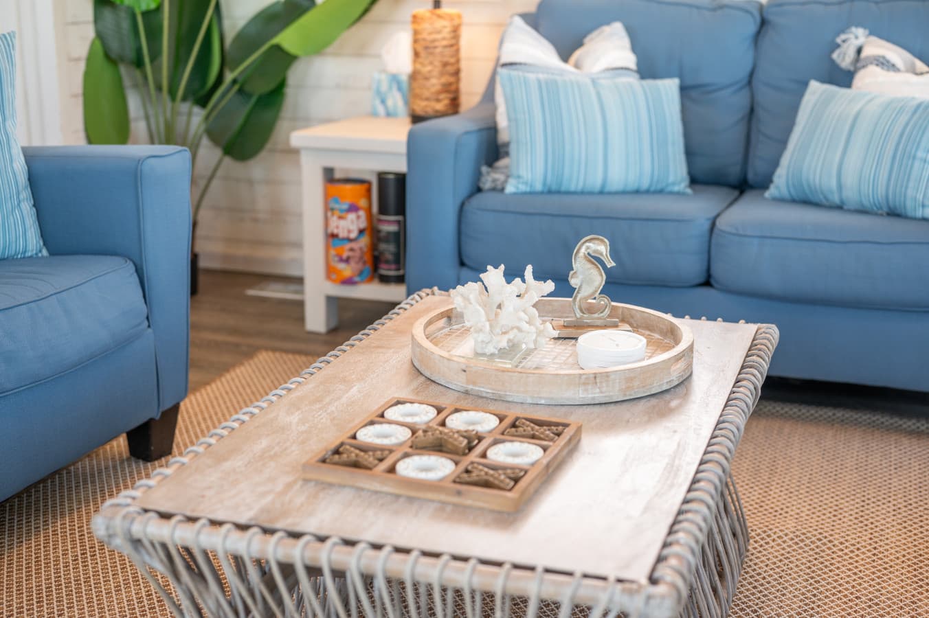 Living room seating w/ blue sofa, armchair & a woven coffee table styled w/ coastal touches.