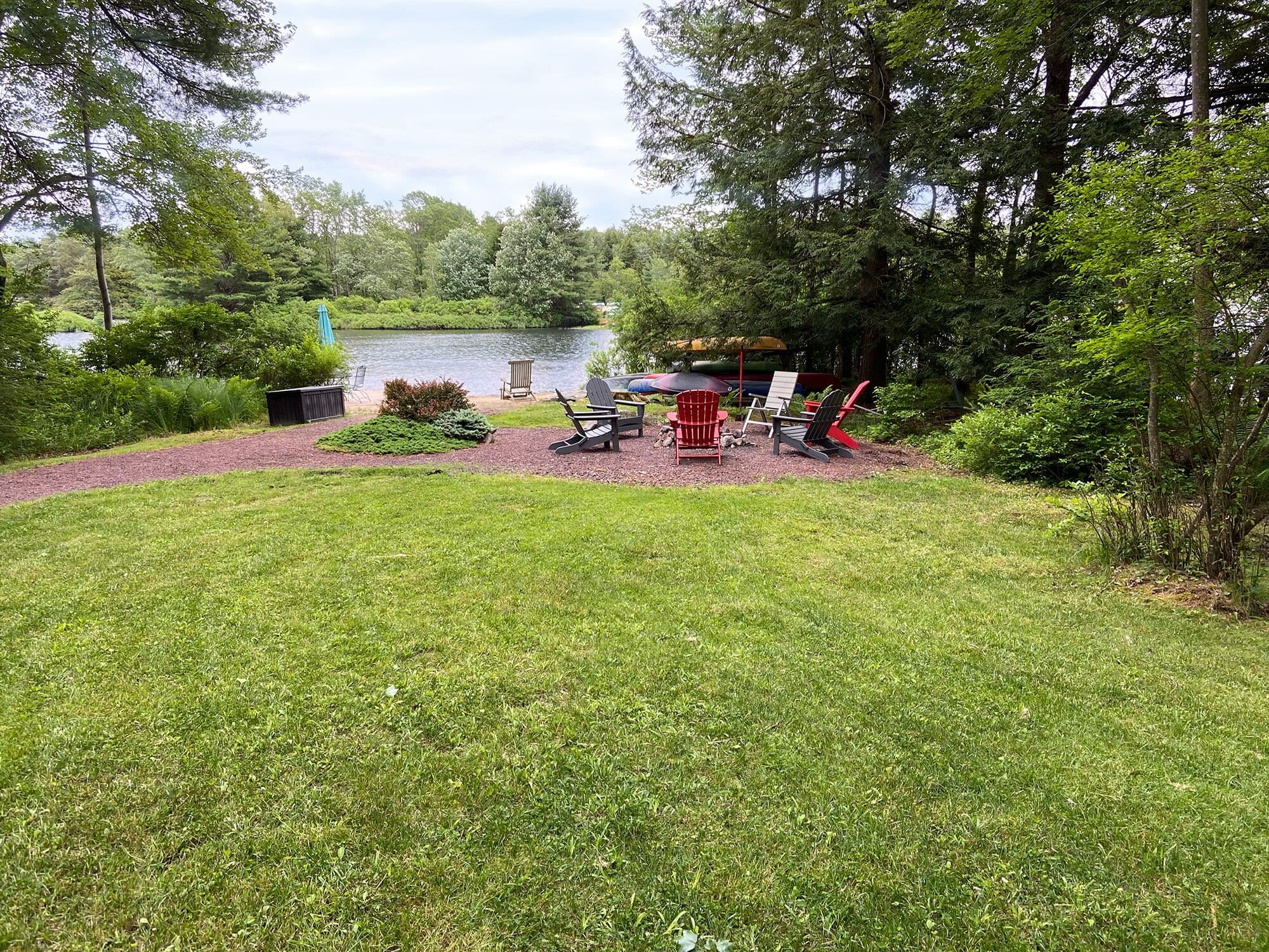 View of the fire pit, sandy beach and dock in the backyard. Play some croquet!