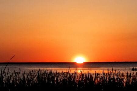 View of guests Kayaking at sunset from our private dock at Runaway Bay Lodge.