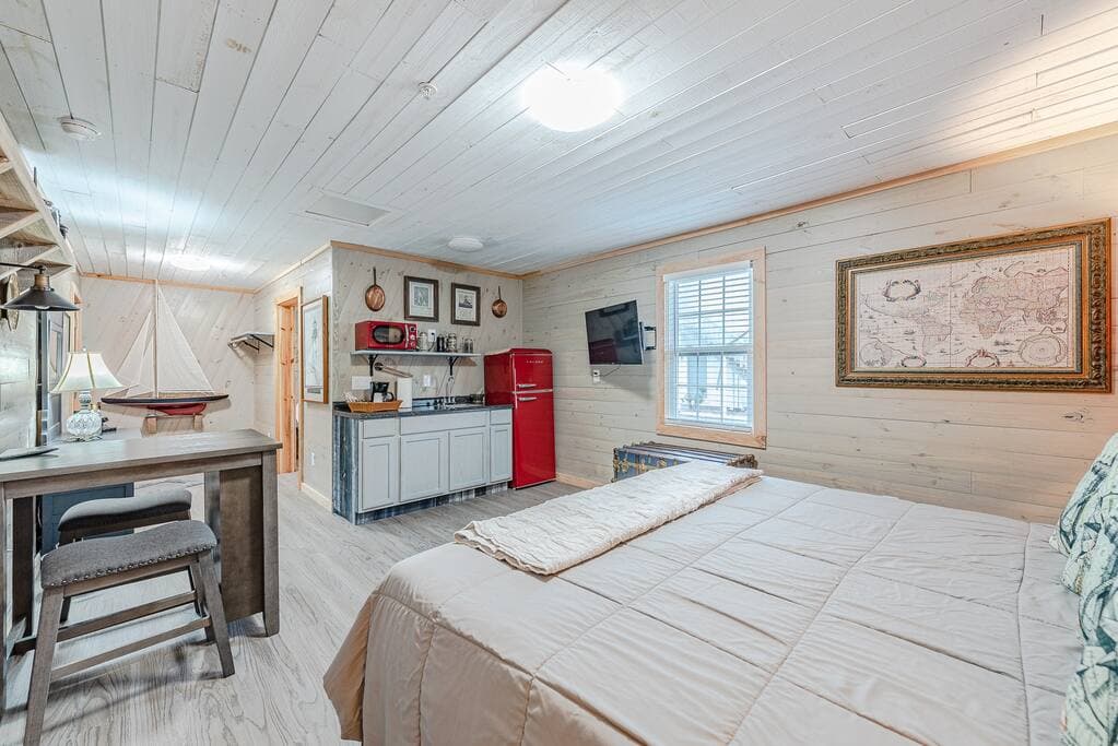 Comfortable bed with TV, mini fridge, kitchenette, workspace, and unique design.