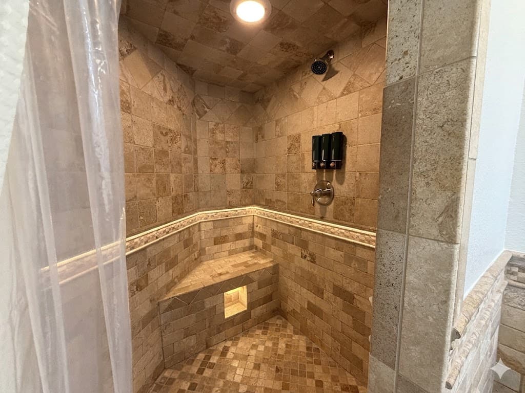 Bathroom 3 — Travertine Stone Walk-In Shower with Built-In Bench & Rain Shower Head | Ensuite for Bedroom 4 at The Mark Twain Estate