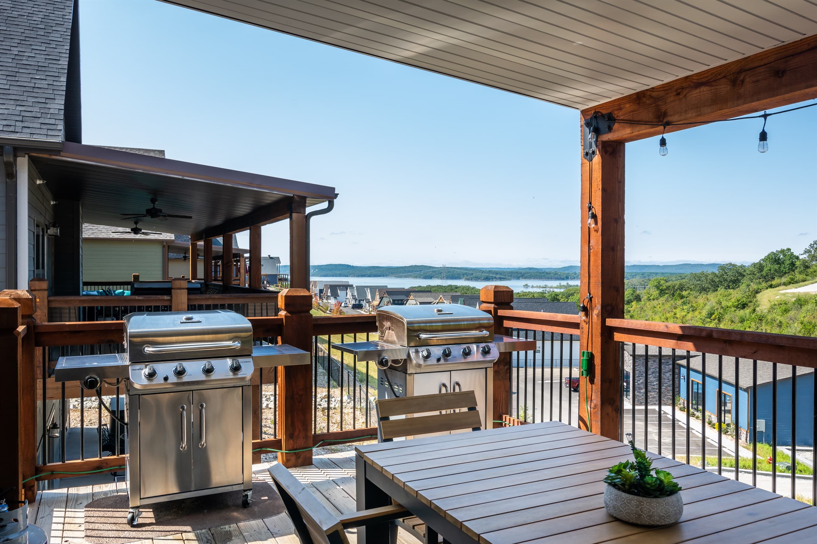 Two stainless steel bbq grills on the deck with a lake view