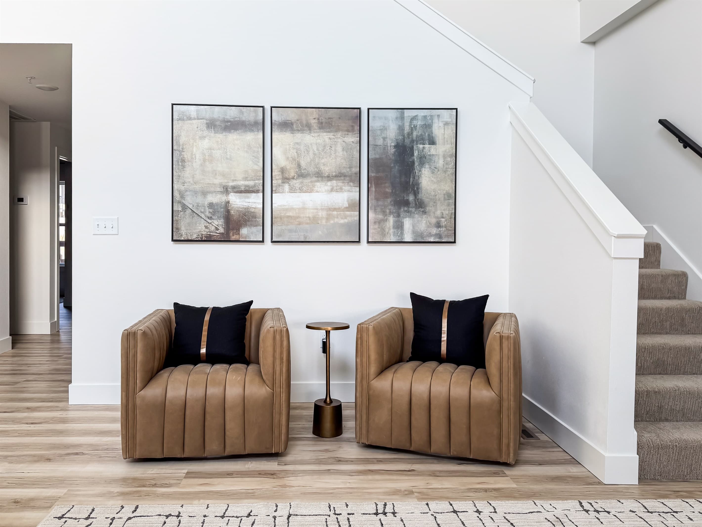 Two leather seats in the living room and stairs that lead to the upper level bedroom suite with king bed
