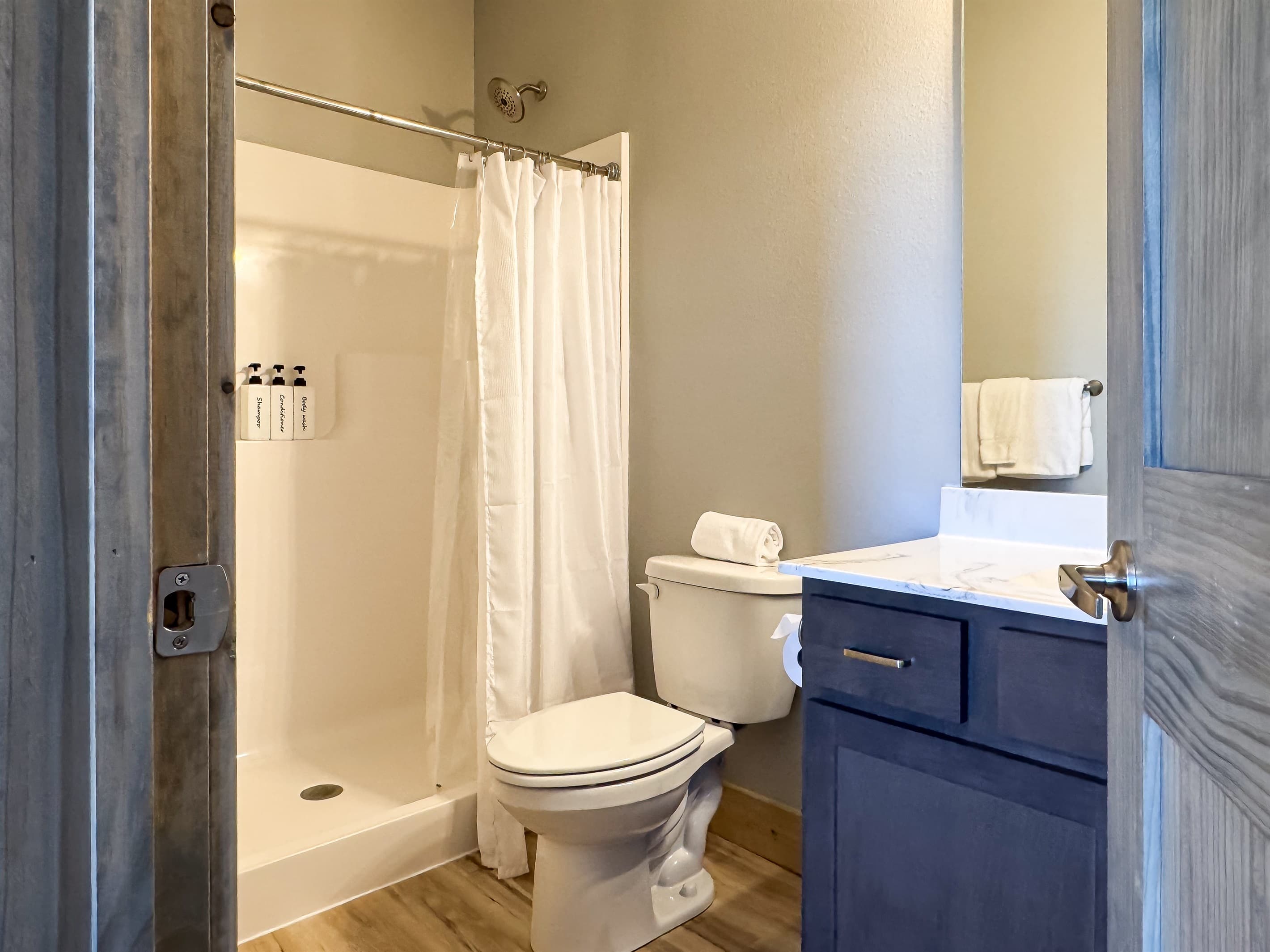 Bedroom 3 En-suite bathroom with low threshold shower, toilet, and vanity with a huge mirror