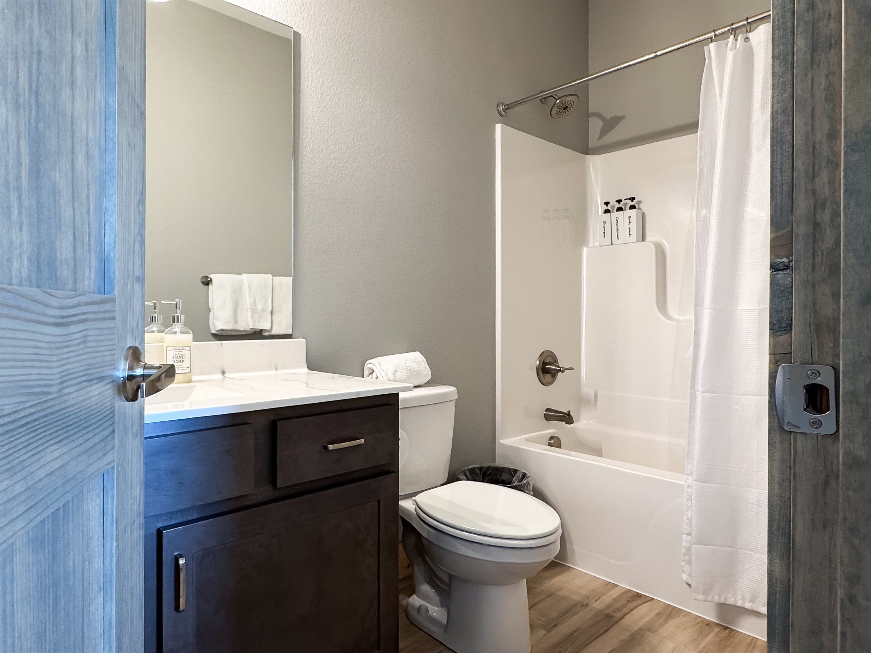 Bedroom 4 En-suite bathroom with tub shower, vanity with huge mirror, and toilet