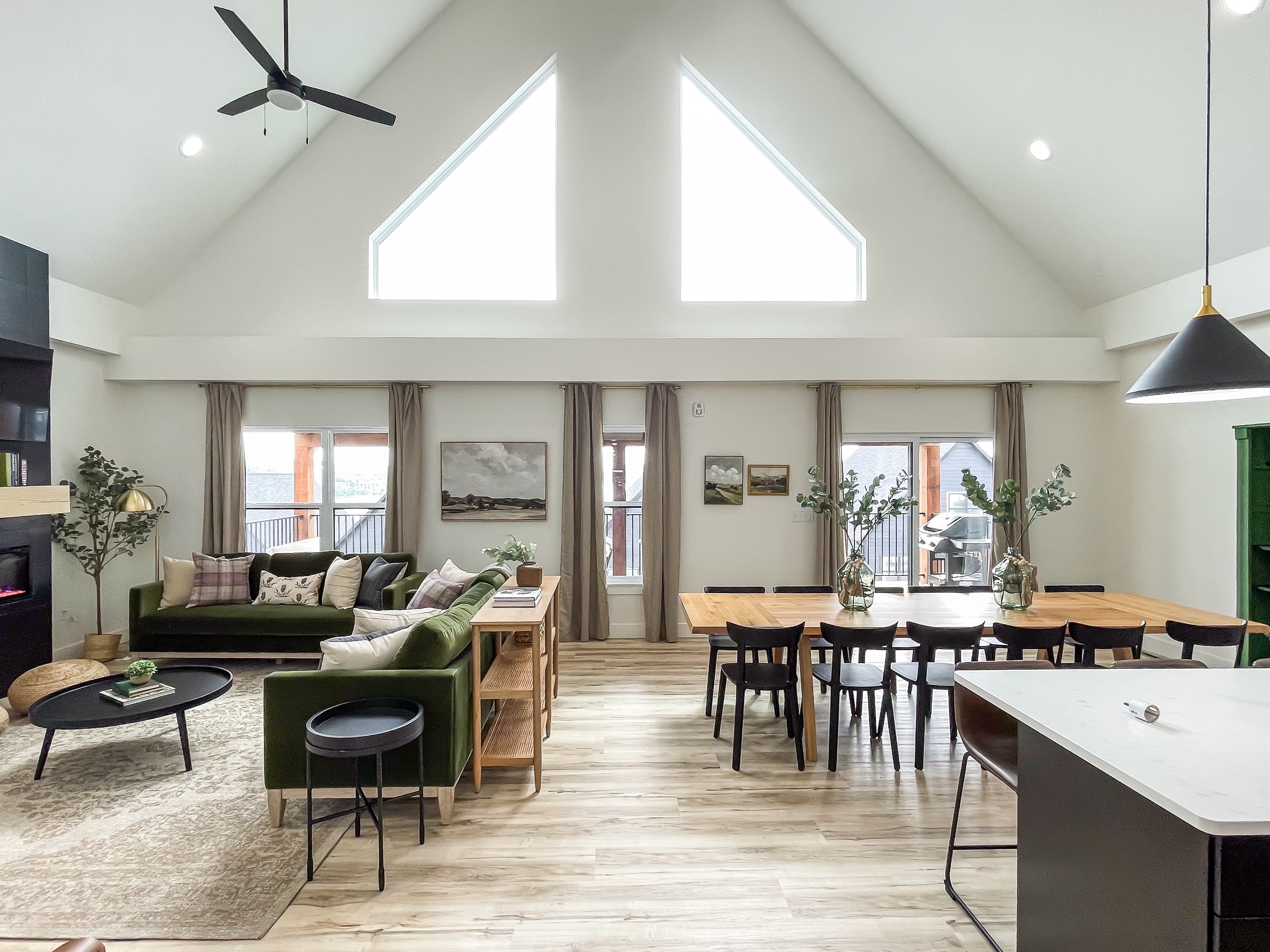 Bright and airy main level great room with vaulted ceilings, soft velvet couches, open concept dining and kitchen area