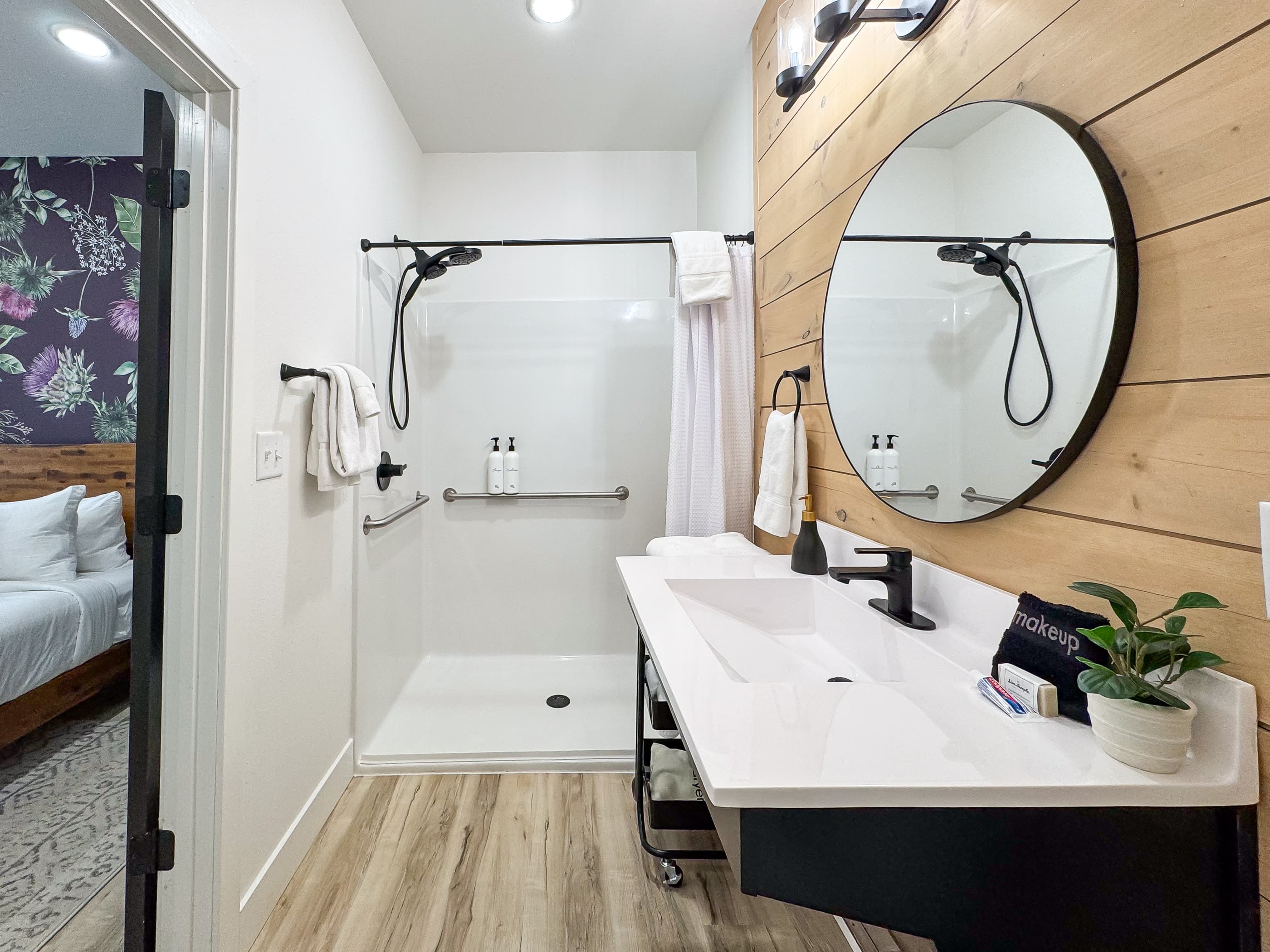 Shower with small lip and flexible water guard. Also features grab bars and handheld shower head inside of the shower