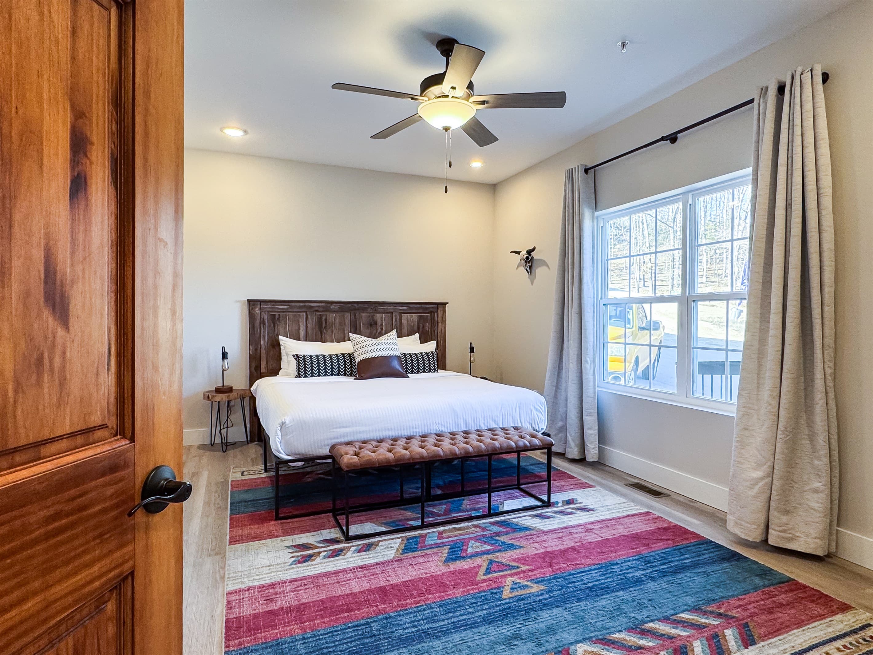 Main level king bedroom with ample room around bed and seating bench