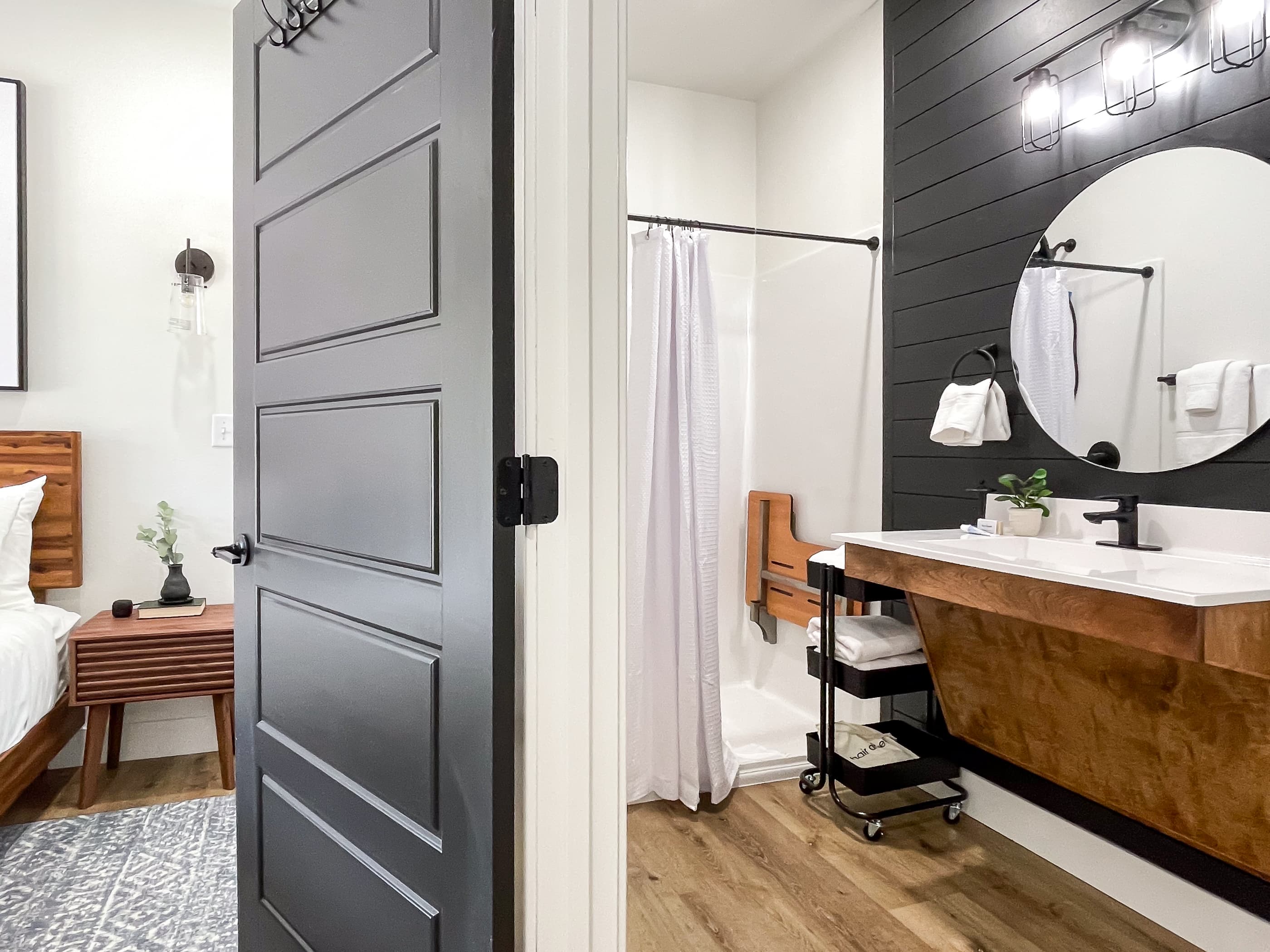 Main level ensuite bathroom with sloped vanity/sink, low lip roll in shower with flexible water guard, and seat