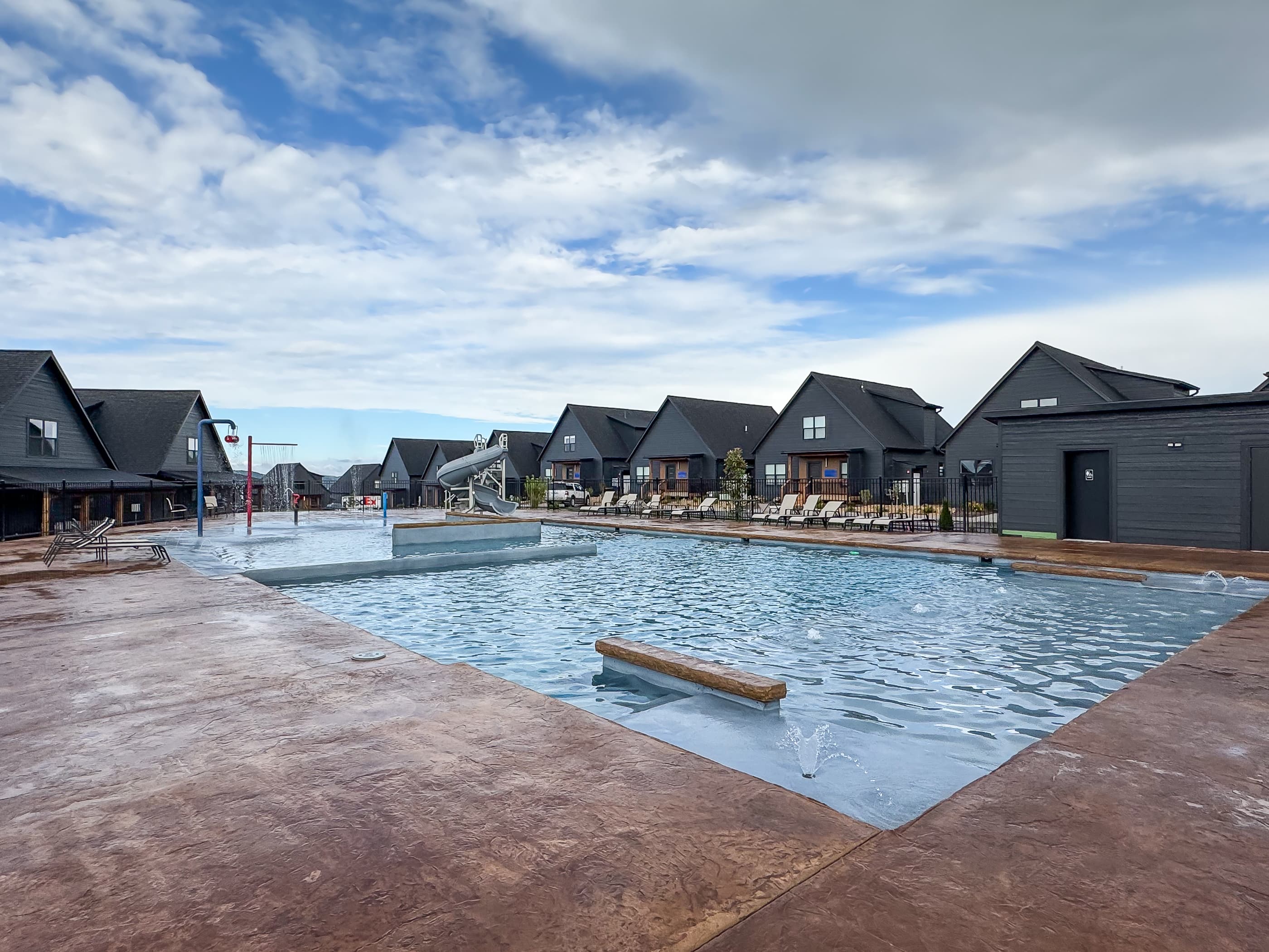 Outdoor pool area with zero entry area by splash pad or stairs to get in the pool