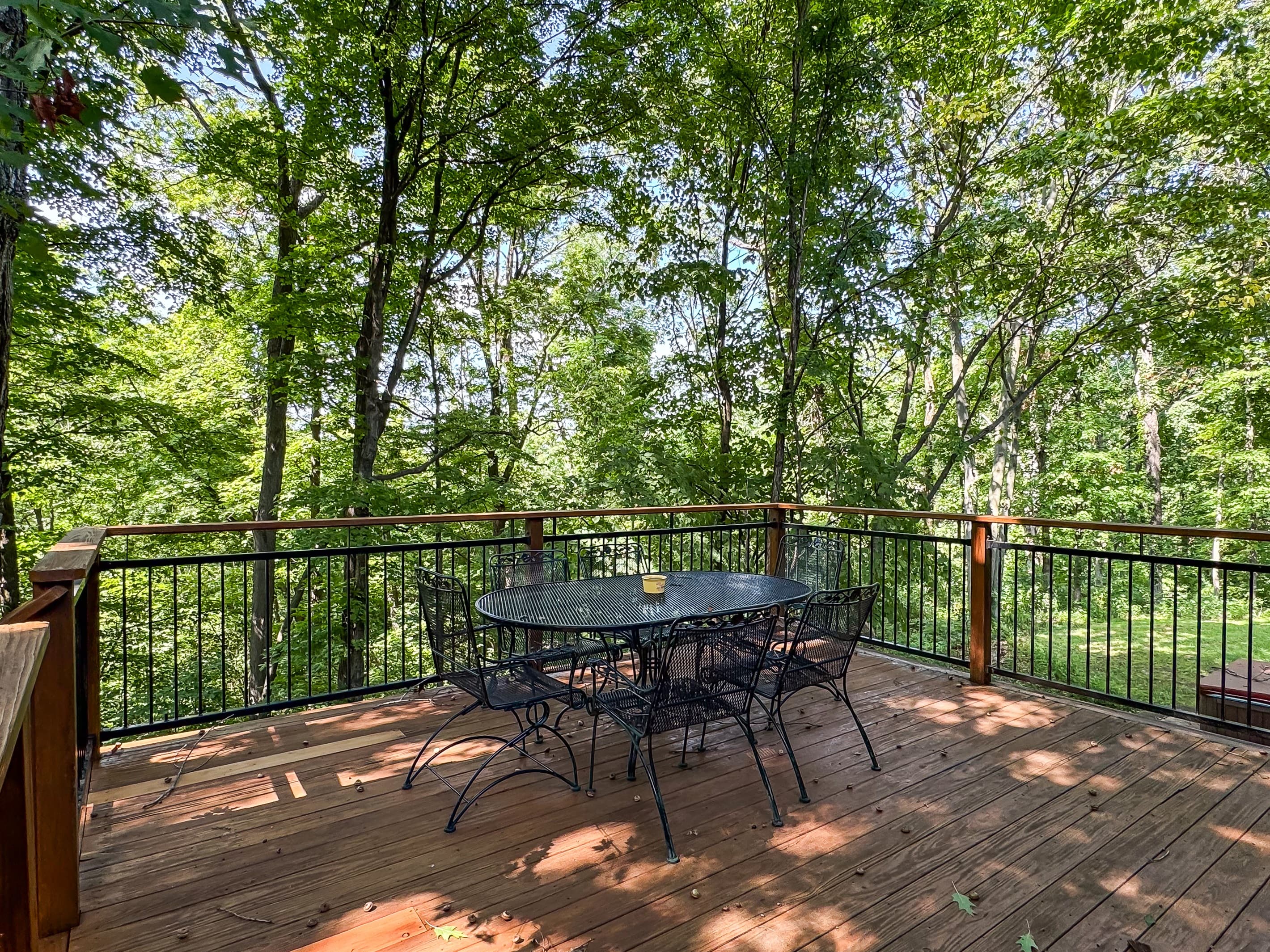 Outdoor dining table and chairs with peaceful tree top views from the back yard deck right outside the kitchen at Pointer Haus.
