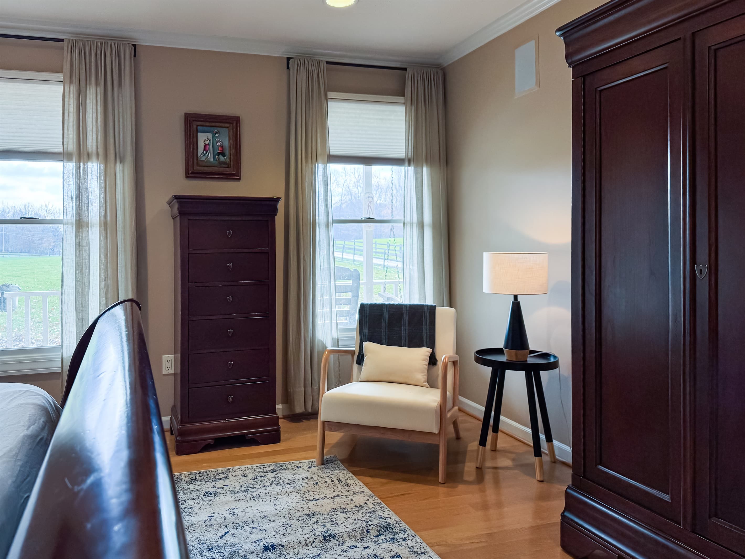 Main Level King Bedroom with chair and table lamp for reading a book in this peaceful farm-like setting at Pointer Haus.