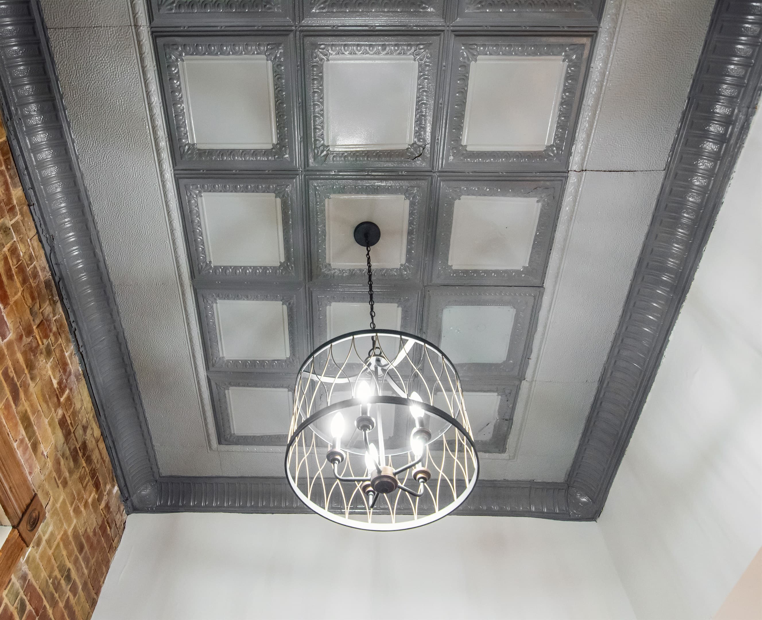 Main entry original ceiling tiles with a modern touch and bright lighting at the Bank Haus.
