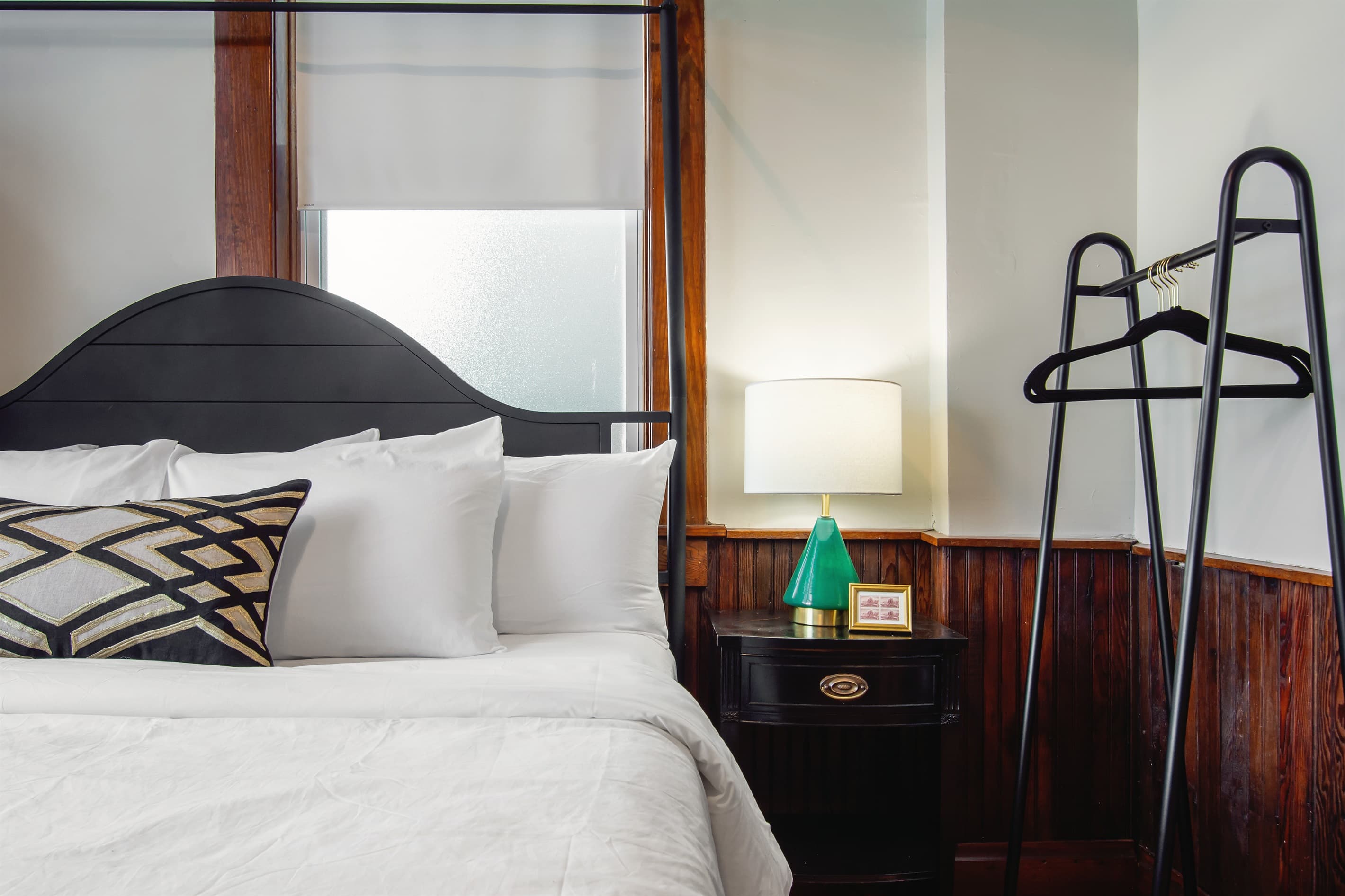 Main level bedroom with side table, luggage rack, clothing rack, and cozy king size bed.