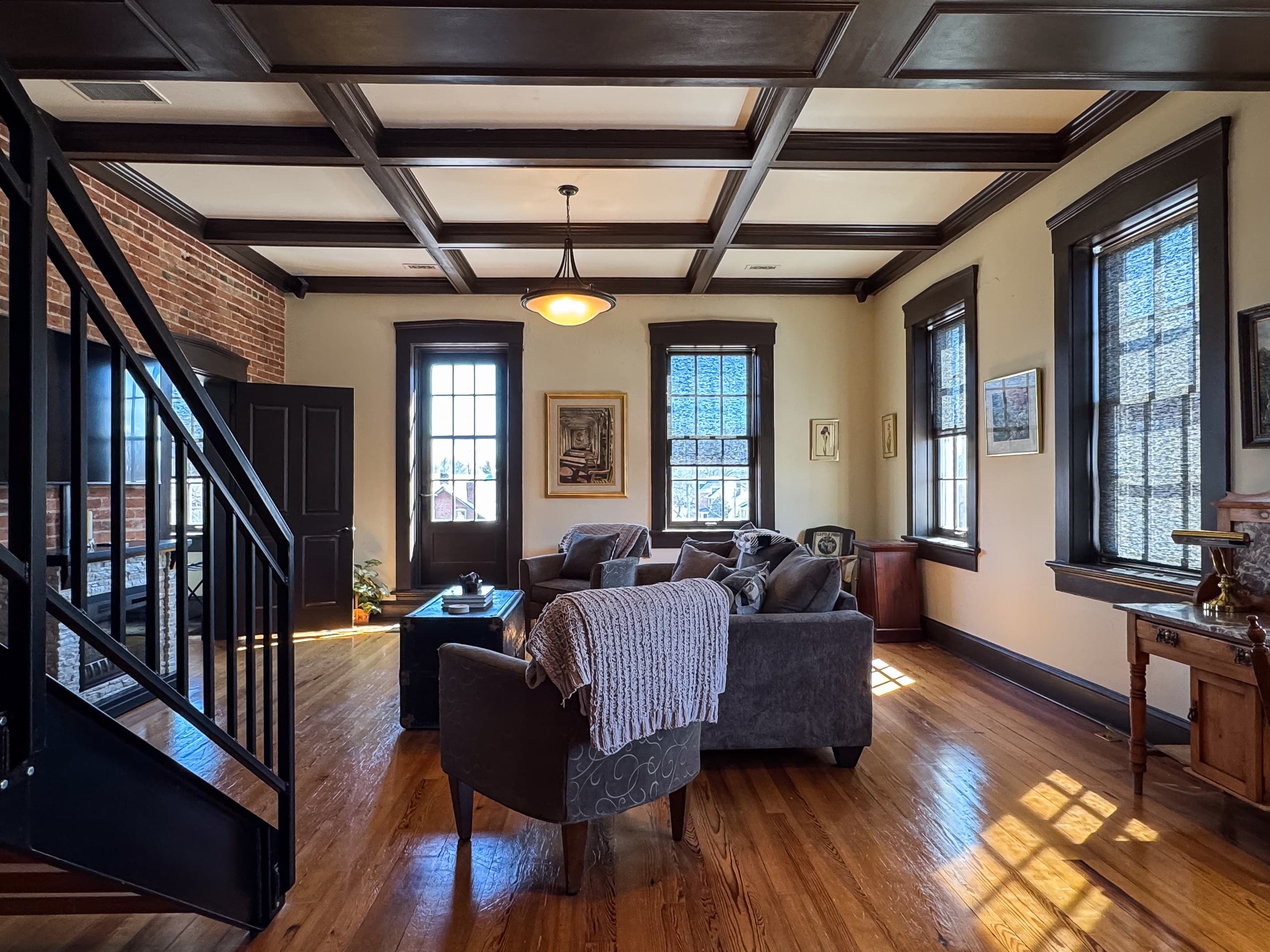Spacious living room with huge windows and tall ceilings and abundant seating that includes a sleeper sofa in downtown Washington, MO at Tamm Loft.