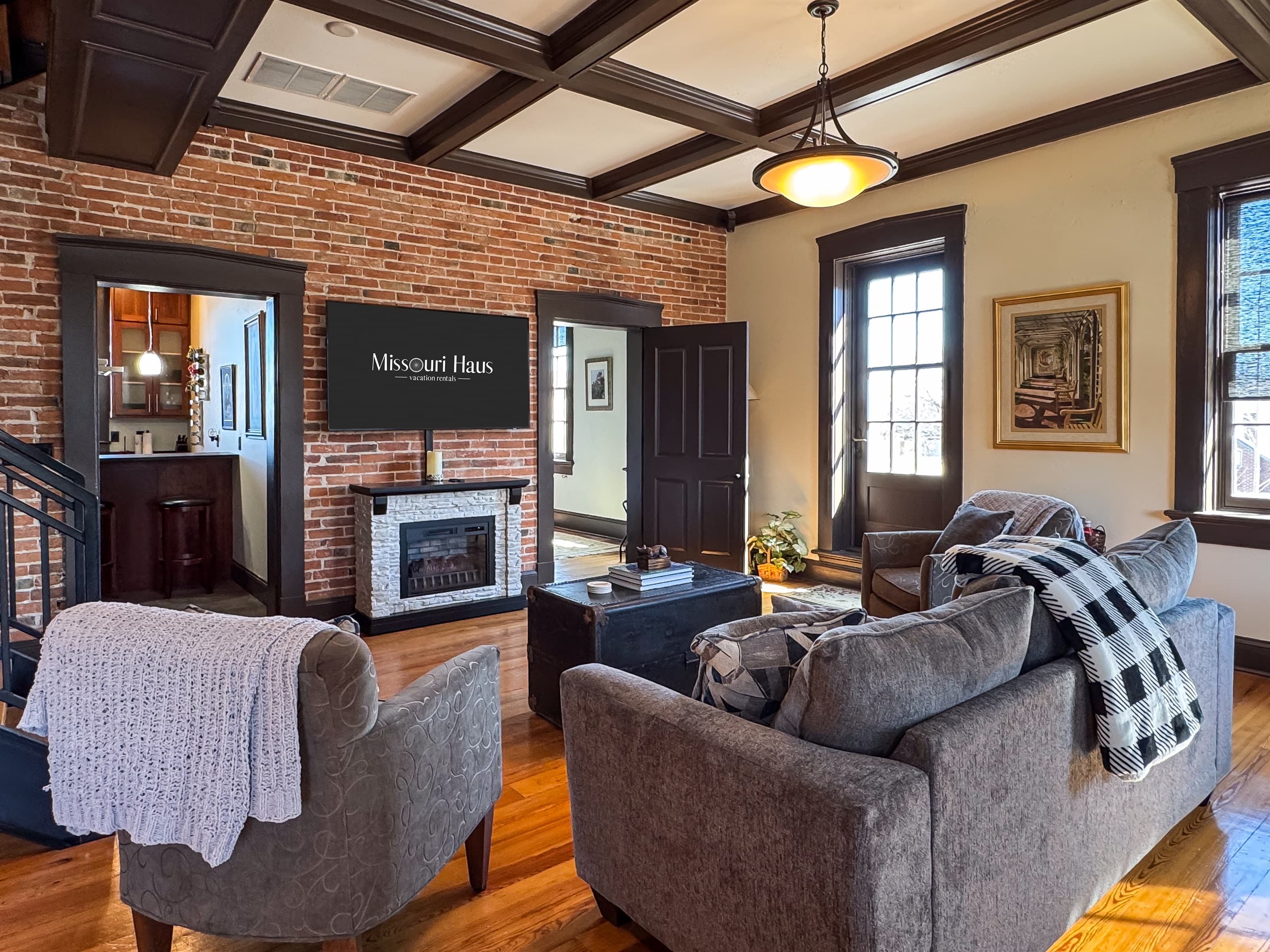 Spacious living room with original exposed brick wall includes a Smart TV for those movie nights cuddled up on the cozy couch in downtown Washington, MO at Tamm Loft.