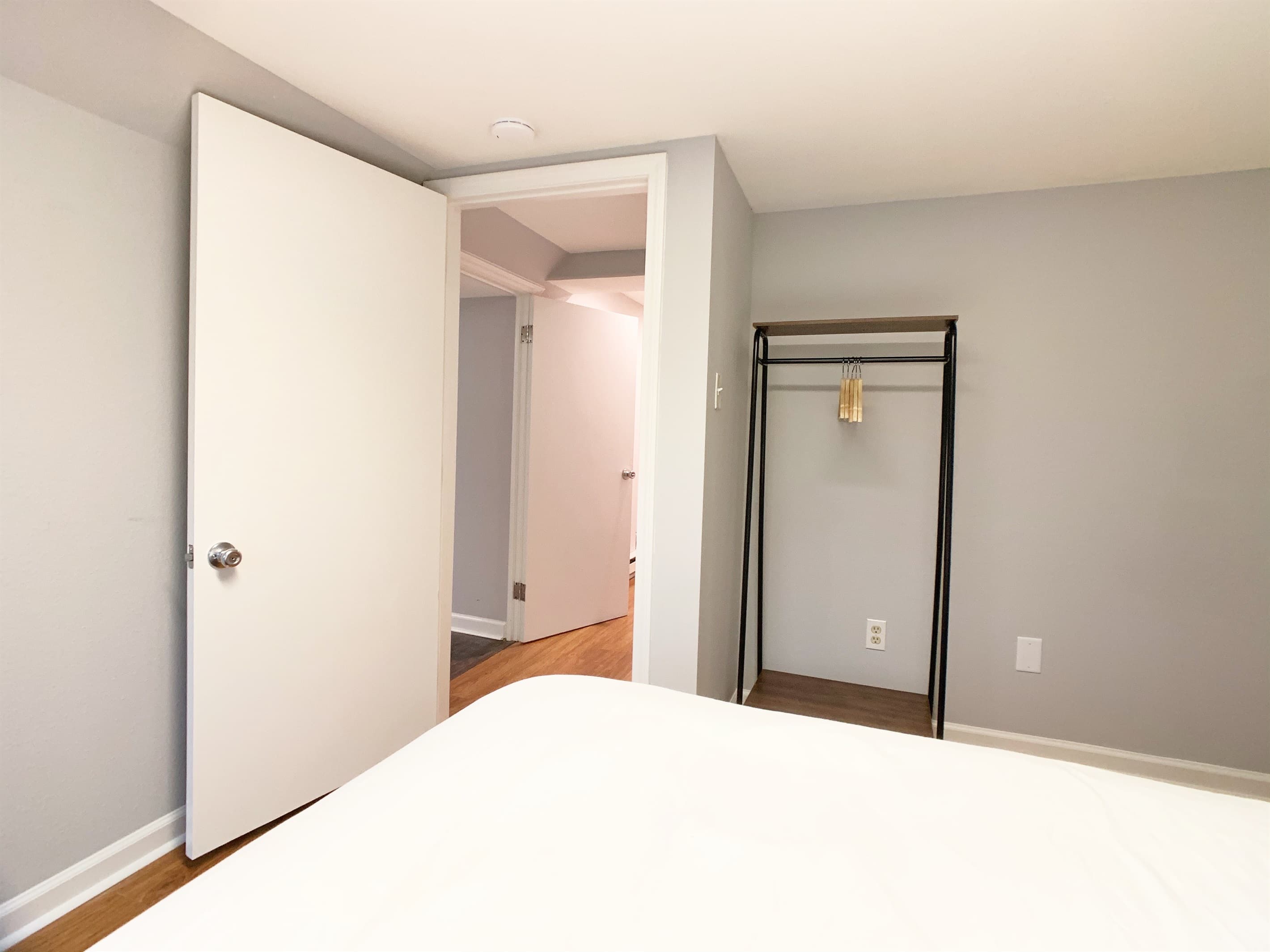 Lower level bedroom 3 with queen bed, luggage/clothing rack and slider door leading to back patio.