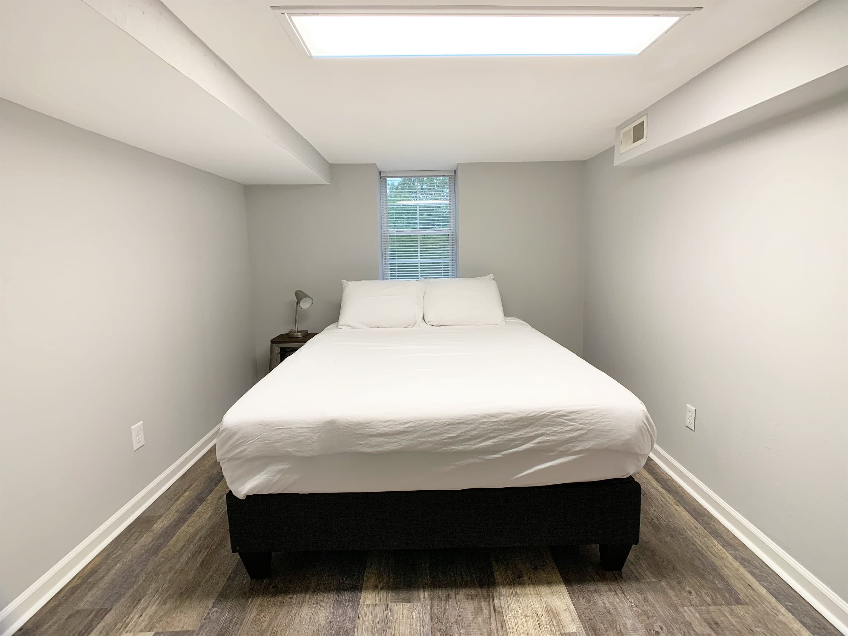 Lower level bedroom 4 with queen bed, luggage/clothing rack and Smart tv.
