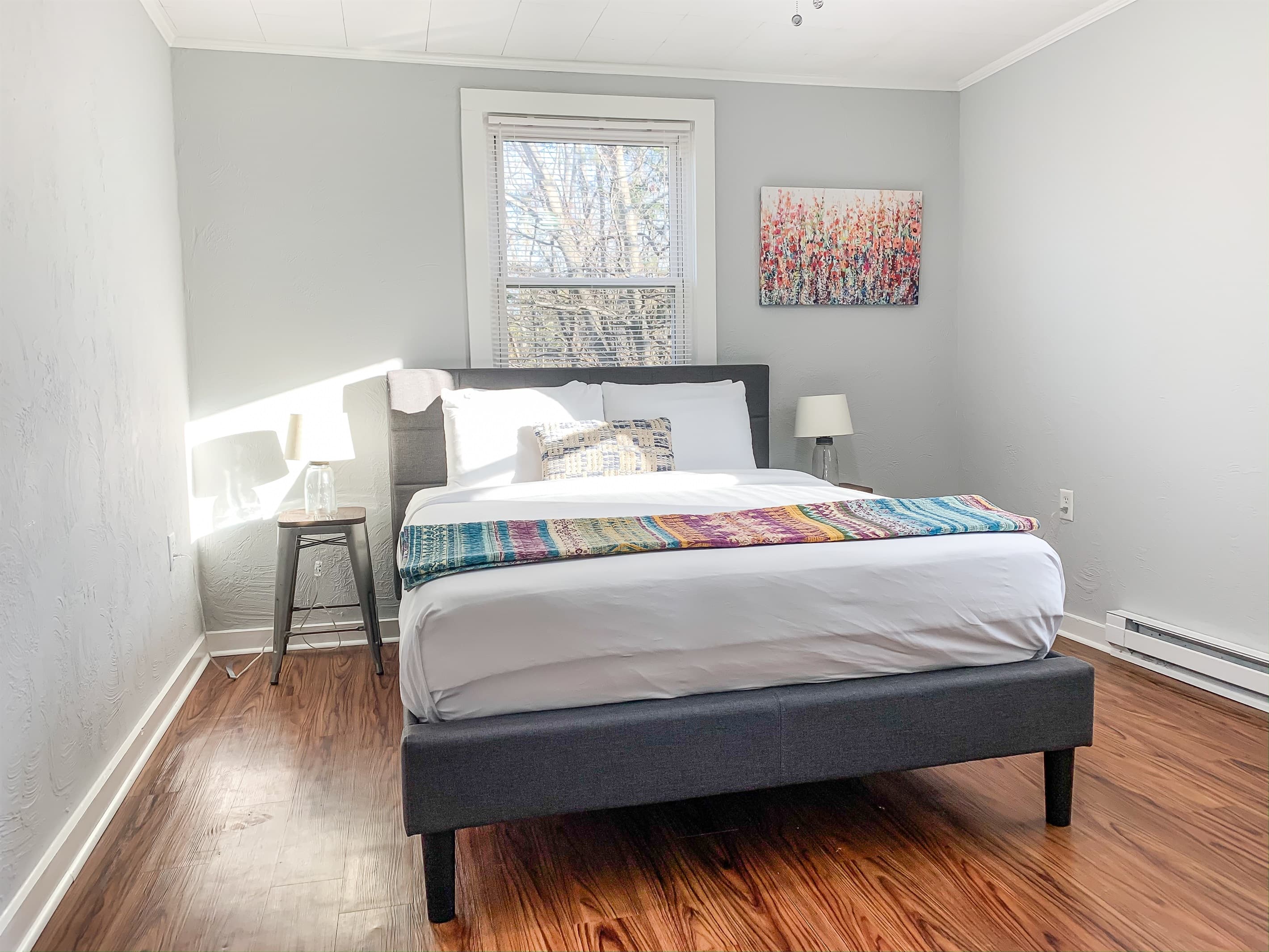 Inviting and spacious bedroom with queen bed and 2 side tables with lamps.
